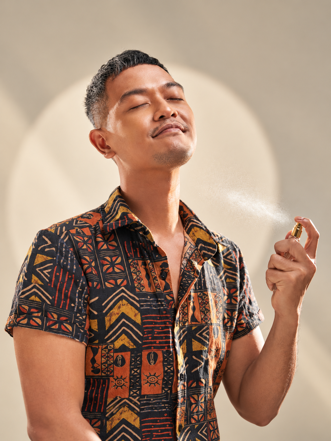 Bobby Shay enjoying a fragrance mist in a warm studio portrait